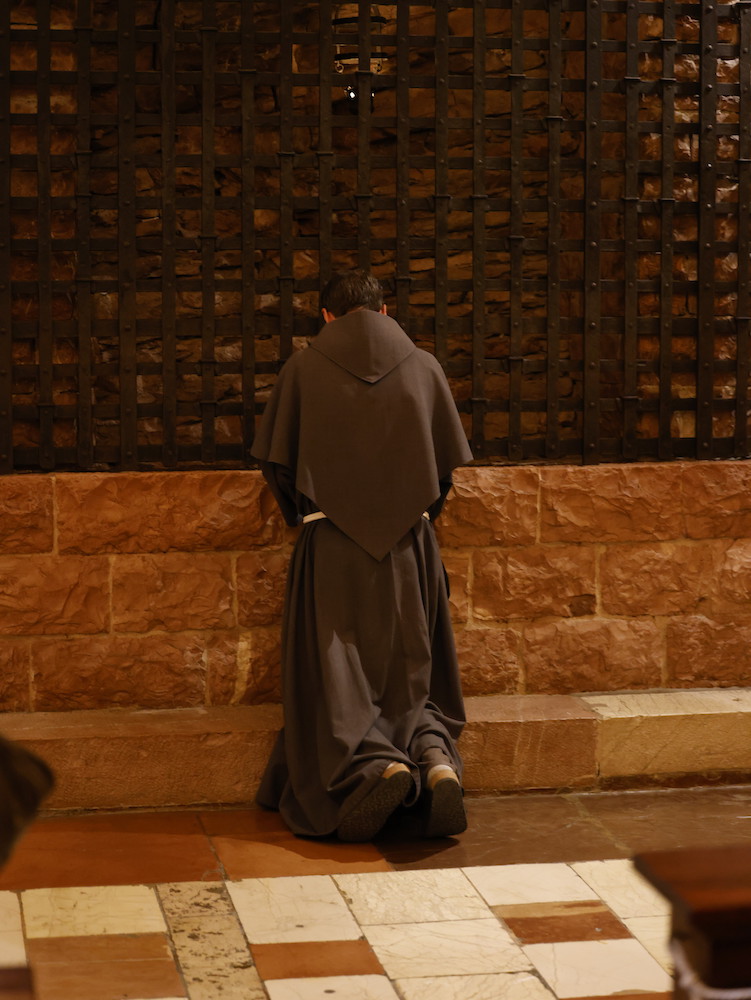Pellegrini in preghiera davanti alle spoglie di San Francesco nella Basilica di Assisi